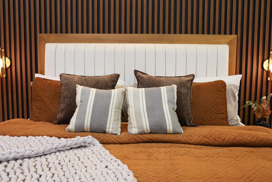 Chambre comme à l'hôtel avec tête de lit capitonnée et coussins superposés